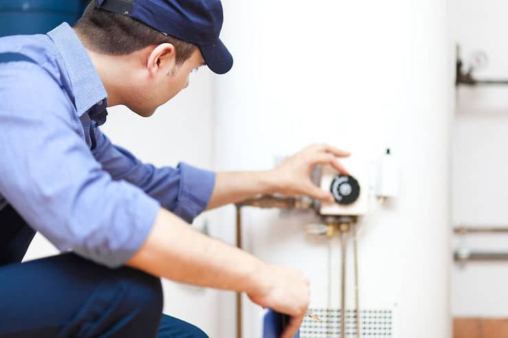 Technician adjusting residential water heater temperature control