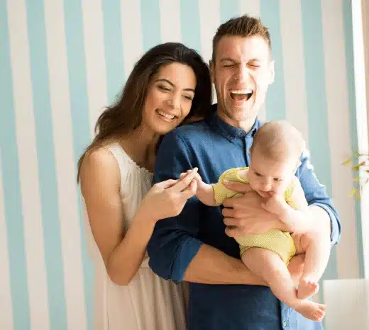 Happy parents holding baby together at home